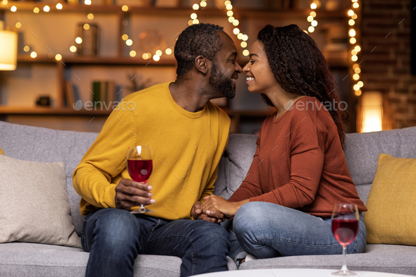 Cheers. Closeup of beautiful smiling young american couple drinking red wine, holding glasses and - Stock Photo - Images