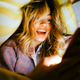 Young cheerful caucasian woman using smartphone, lies under a blanket on a bed at home - PhotoDune Item for Sale