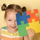 Kid cheerfully while closing eye holding puzzle of colorful details in hand - PhotoDune Item for Sale