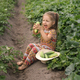 A little laughing girl holds large fresh cucumber plucked from garden. - PhotoDune Item for Sale
