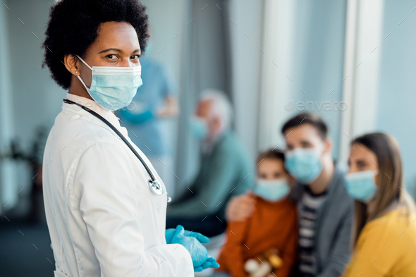 African American female doctor wearing protective face mask at hospital hallway.