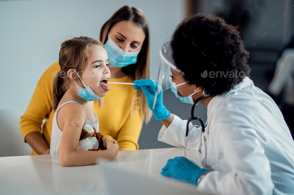 Little girl having throat exam at pediatrician\'s office during COVID-19 pandemic.