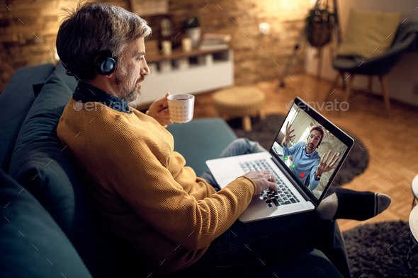 Male entrepreneur having video call over laptop in the evening at home.