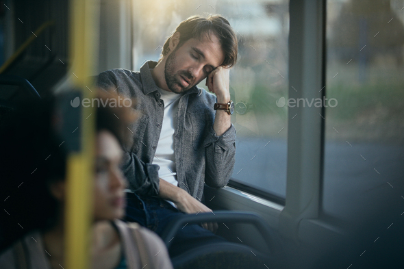 Mid adult man taking a nap while traveling by public transport.