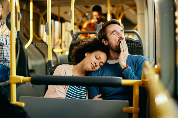 Exhausted couple commuting together by bus.