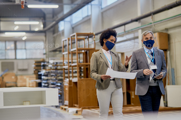 Company managers communicating while visiting woodworking production facility during coronavirus.