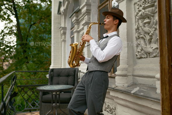 Young male musician practicing saxophone in balcony at home