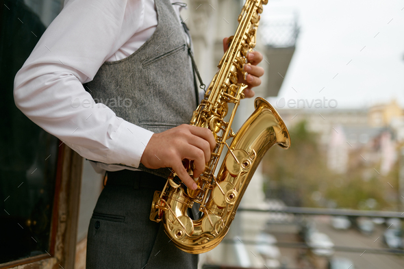 Saxophonist playing music outdoors, closeup saxophone in musician hand - Stock Photo - Images