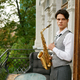Young man holding saxophone standing on balcony terrace - PhotoDune Item for Sale