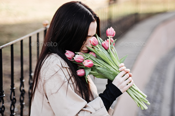 Spring, self love, self care. Candid portrait of happy woman with tulips bouquet outdoors