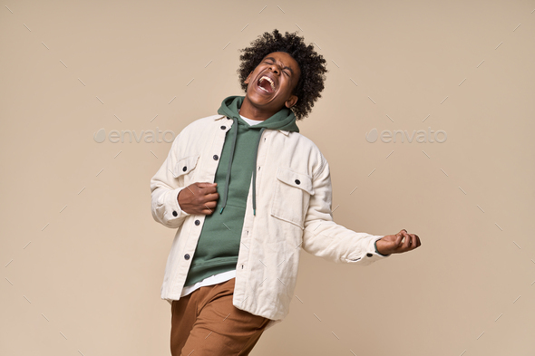 Cool funky African American teen pretending playing guitar isolated on beige. - Stock Photo - Images