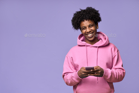 Happy African teen guy holding cellphone using mobile phone isolated on purple. - Stock Photo - Images
