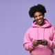 Happy African teen guy holding cellphone using mobile phone isolated on purple. - PhotoDune Item for Sale