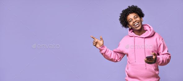 Happy African teenager holding mobile phone pointing finger presenting app. - Stock Photo - Images