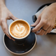 Thin female fingers hold a cup of coffee with heart shaped latte art foam.  - PhotoDune Item for Sale