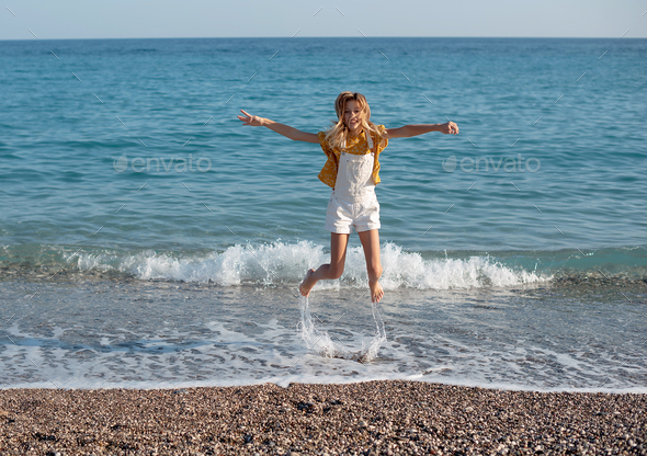 Cute child girl jumping on the beach - Stock Photo - Images