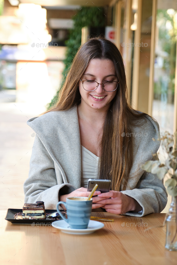 Smiling woman using the phone in a coffee shop. - Stock Photo - Images