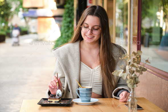 Woman eating a cake and drinking coffee in a cafe. - Stock Photo - Images