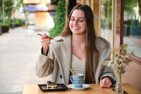 Woman eating a cake and drinking coffee in a cafe. - Stock Photo - Images