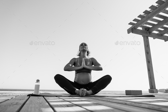 Pregnant woman doing yoga meditation on the beach - Maternity and