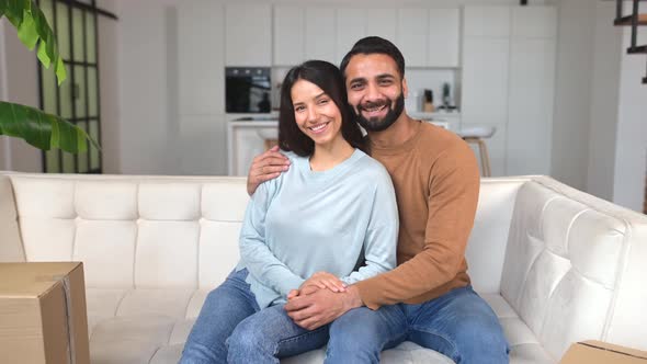Happy Smiling Indian Couple in Love Sitting on the Sofa in Surrounded with Cardboard Boxes
