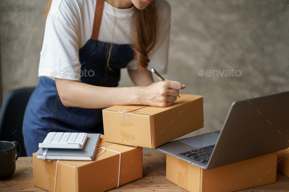Online business owner woman check customer lists to properly pack and ship to customers.
