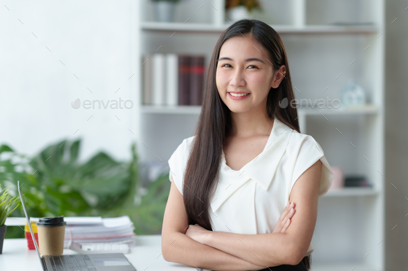 Beautiful Asian businesswoman sitting smiling, cross arms and opened her laptop and happily looking  - Stock Photo - Images