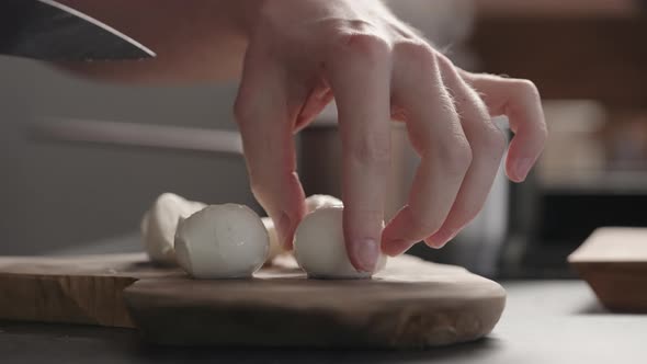 Slow Motion Man Slicing Medium Sized Mozzarella Balls with Knife on Olive Wood Board alt