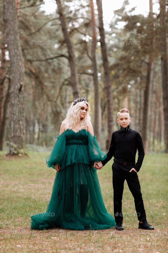 young beautiful blonde woman queen with young boy in black outfit. Princess  mother walks with son Stock Photo by andriymedvediuk