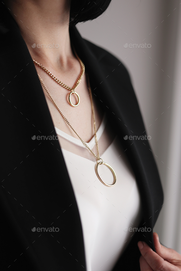 Decoration on a woman\'s neck. A woman in a black jacket and white blouse, cropped view. Stylish
