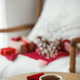 Cute stylish cup of tea with heart and red envelope on wooden table against modern armchair - PhotoDune Item for Sale
