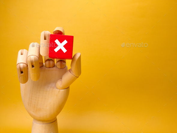 Wooden hand holding red cube with error sign.Concept of negative decision making or choice of vote w - Stock Photo - Images