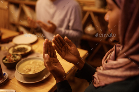 Close up of Middle Eastern woman praying with husband at dining table. - Stock Photo - Images