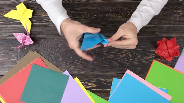 Man Doing Origami Crane, Top View. alt