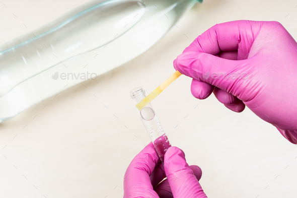 hand holds neutral litmus paper on test tube - Stock Photo - Images
