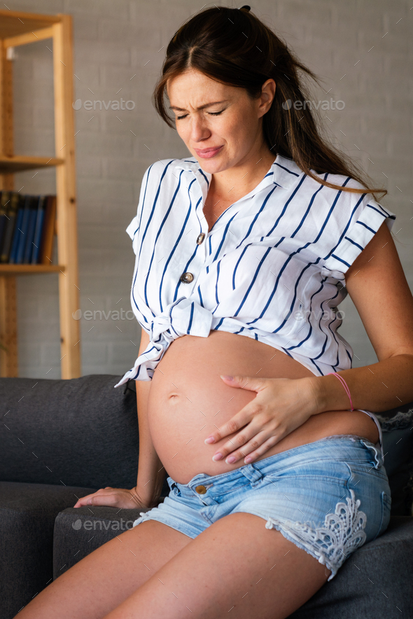 Pregnant woman having abdominal and back aches in the last trimester of pregnancy at home - Stock Photo - Images