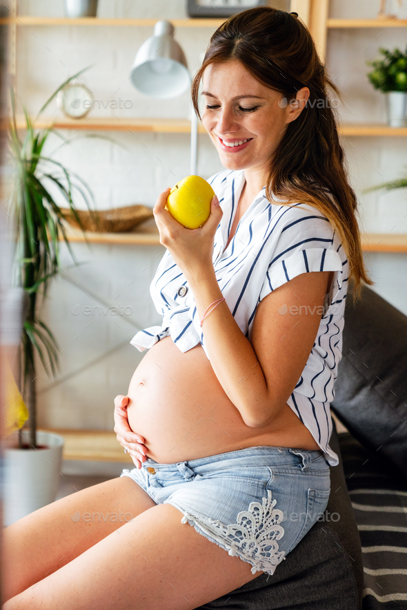 Pregnancy, healthy food and people concept Happy pregnant woman eating apple. healthy food. - Stock Photo - Images