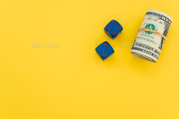 Bundle of rolled-up American banknotes and two dice isolated on a yellow background - Stock Photo - Images