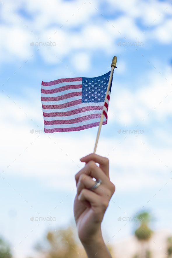 Vertical shot of a hand waving an American flag outdoors