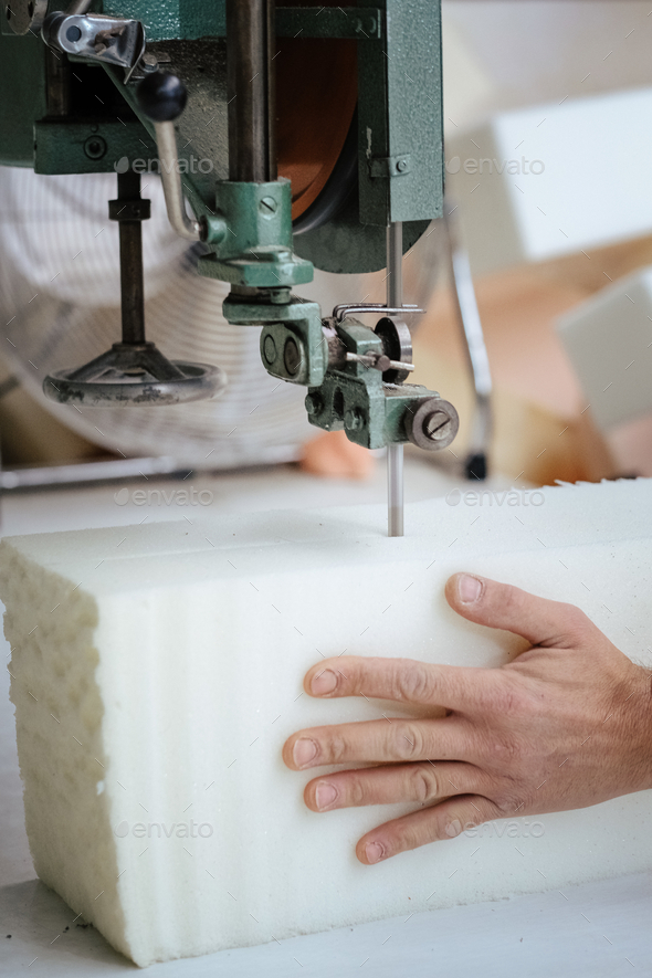 Vertical shot of a furniture maker cutting an upholstery foam using a foam cutter machine