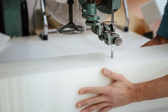 Furniture maker cutting an upholstery foam using a foam cutter machine