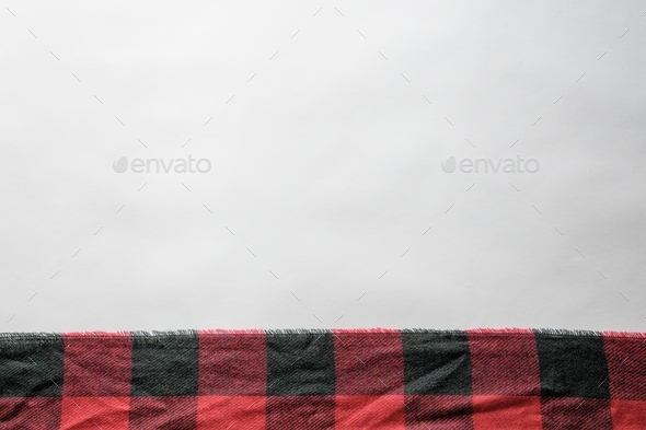 Red and black flannel texture on a white surface with empty space for text