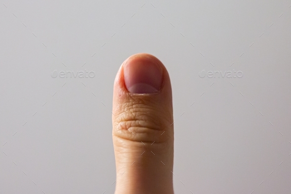 Closeup of a human thumb under the lights against a white background