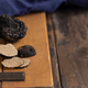 Whole and sliced black truffles mushroom on wooden board on dark brown table, close up - PhotoDune Item for Sale