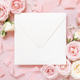 Square envelope between pink roses and pink silk ribbons on pink top view, wedding mockup - PhotoDune Item for Sale