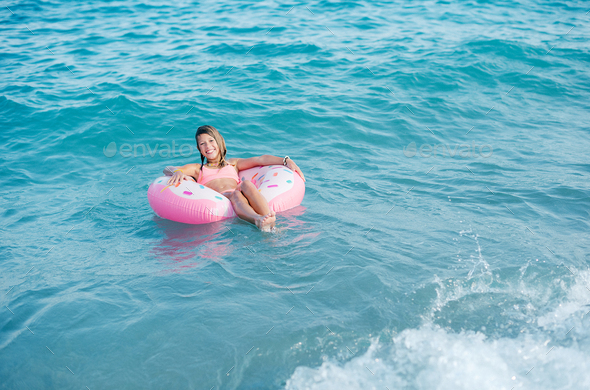 Beautiful young girl with inflatable ring relaxing in the sea - Stock Photo - Images