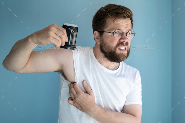 Irritated man sweats a lot and use an antiperspirant to prevent the smell of armpit sweat.