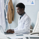 Young black doctor using laptop in office typing working in clinic - PhotoDune Item for Sale