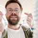 Camera view from the kitchen cabinet of a cute smiling man putting away clean wine glasses on shelf - PhotoDune Item for Sale