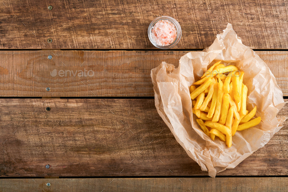French fries. Tasty French fries server on parchment paper on wooden cutting board with tomato and c - Stock Photo - Images